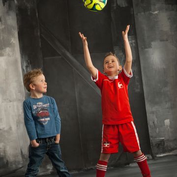 zweier Kinderportrait spielend mit Fussball